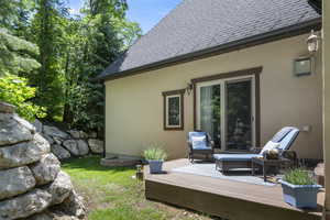 Back of house featuring a wooden deck, roof with shingles, and stucco siding