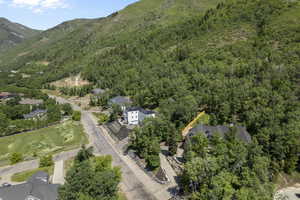 Aerial view of property and surrounding area featuring a forest and a mountainous background