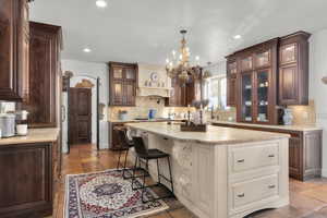 Kitchen featuring sink, backsplash, butcher block counters, and a kitchen island with sink