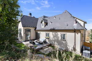 Back of property featuring an outdoor hangout area, a chimney, roof with shingles, stucco siding, and a wooden deck