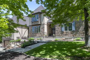 View of front of property with stone siding, stucco siding, and a front lawn