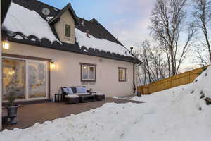 Snow covered house featuring a wooden deck and an outdoor hangout area