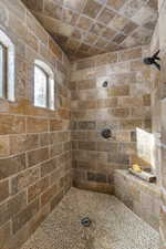 Bathroom featuring brick ceiling and a tile shower