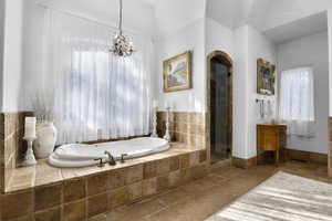 Bathroom with tiled tub and a chandelier