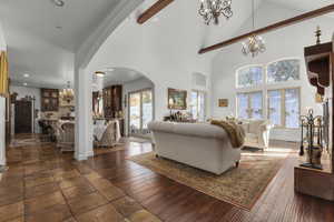 Living room featuring a notable chandelier, high vaulted ceiling, beam ceiling, and dark hardwood / wood-style flooring