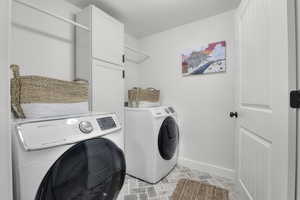 Clothes washing area featuring cabinets and washing machine and dryer