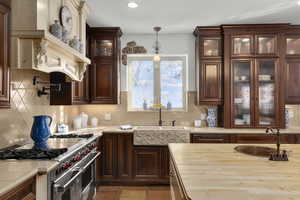 Kitchen with sink, backsplash, range with two ovens, and pendant lighting