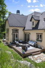 Rear view of property featuring an outdoor hangout area, stucco siding, a wooden deck, and a chimney