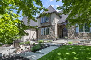 Tudor-style house featuring stone siding, stucco siding, a front yard, and a shingled roof