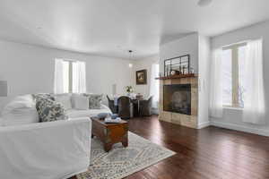 Living room with a fireplace, a healthy amount of sunlight, and dark hardwood / wood-style flooring