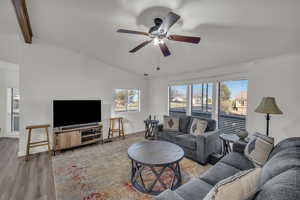 Living room with vaulted ceiling with beams, wood-type flooring, and ceiling fan