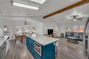 Kitchen featuring a kitchen island, blue cabinets, dishwasher, wood-type flooring, and hanging light fixtures