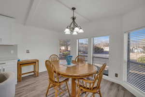 Dining space featuring a notable chandelier, lofted ceiling with beams, and light hardwood / wood-style floors