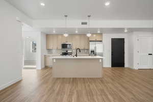 Kitchen featuring sink, light brown cabinets, an island with sink, and appliances with stainless steel finishes