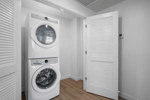 Washroom featuring stacked washer and dryer and hardwood / wood-style floors