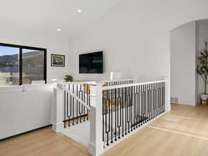 Stairway with vaulted ceiling and hardwood / wood-style floors