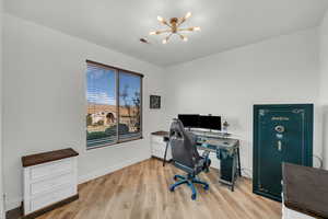 Office with light wood-type flooring and a chandelier