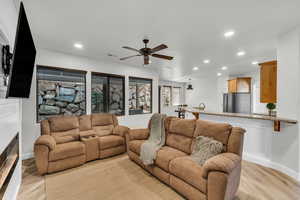 Living room with ceiling fan and light hardwood / wood-style flooring