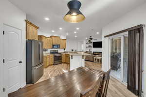 Kitchen featuring light hardwood / wood-style flooring, sink, light stone counters, a breakfast bar, and stainless steel appliances