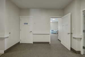 Hall featuring dark colored carpet