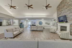 Living room featuring a fireplace, light wood-type flooring, built in shelves, and high vaulted ceiling