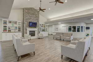 Living room featuring high vaulted ceiling, a stone fireplace, and light wood-type flooring