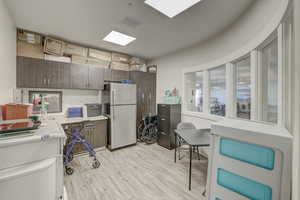 Kitchen with dark brown cabinets, light wood-type flooring, and stainless steel refrigerator
