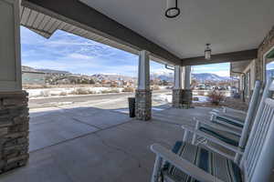 Snow covered patio featuring a mountain view and a porch