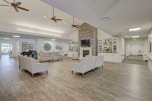 Living room featuring a textured ceiling, built in shelves, a fireplace, light wood-type flooring, and high vaulted ceiling