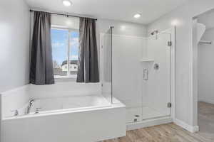 Bathroom with independent shower and bath and wood-type flooring