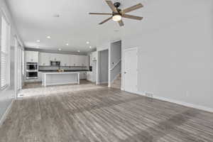 Unfurnished living room with a textured ceiling, ceiling fan, and light wood-type flooring