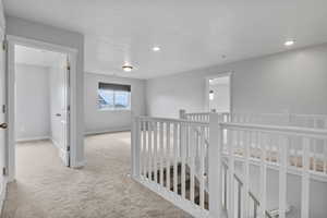 Hallway featuring light carpet and a textured ceiling