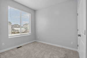 Empty room featuring light carpet and a textured ceiling