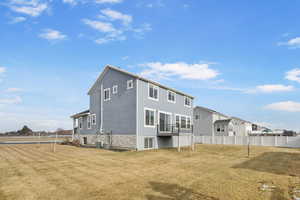 Rear view of house with cooling unit and a lawn