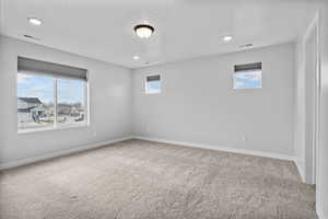 Carpeted spare room featuring plenty of natural light and a textured ceiling