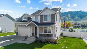 Craftsman-style home with a front lawn, fence, and driveway