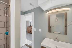 Bathroom with tiled shower, vanity, toilet