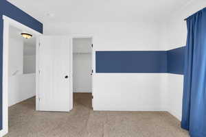 Unfurnished bedroom featuring carpet flooring and a spacious closet