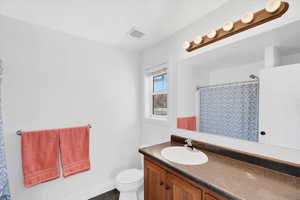 Bathroom featuring vanity, a shower with shower curtain, tile patterned floors, and toilet