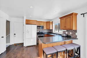 Kitchen with dark wood-type flooring, sink, a kitchen breakfast bar, kitchen peninsula, and stainless steel appliances