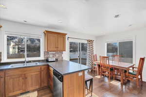Kitchen featuring dark wood-type flooring, sink, stainless steel dishwasher, kitchen peninsula, and backsplash