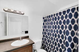 Bathroom with vanity, vaulted ceiling, and toilet