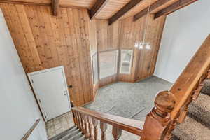 Interior space with beamed ceiling, wooden ceiling, and wood walls