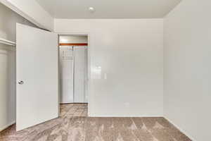 Unfurnished bedroom featuring light carpet and a closet