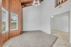 Unfurnished room featuring a chandelier, high vaulted ceiling, wooden ceiling, beamed ceiling, and light colored carpet