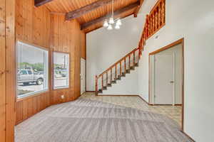 Foyer entrance with beamed ceiling, high vaulted ceiling, a chandelier, and wood ceiling