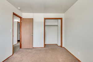 Unfurnished bedroom with light carpet and a closet