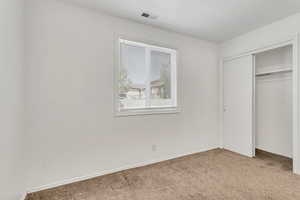 Unfurnished bedroom with light carpet and a closet