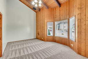 Unfurnished room with wood ceiling, an inviting chandelier, beam ceiling, high vaulted ceiling, and light colored carpet