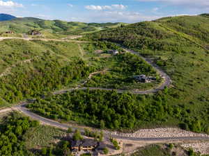 Aerial view of property and surrounding area with a forest and a mountain backdrop